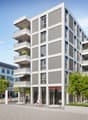 Modern apartment building with multiple balconies, glass windows, and a ground floor with commercial space.
