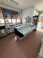 empty room with tiled floor, glass display case, microwave, refrigerator, and posters on the wall