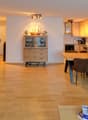 open living area with dining table and couch, wooden floor, large window, TV on stand, kitchen, cabinet, dining table with chairs