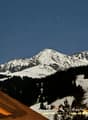 Mountain view from a house roof, snowy mountains, trees, night sky