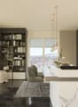 Spacious open-concept living room and kitchen with large windows providing a scenic view. The room features a built-in bookshelf, a dining table, and modern kitchen appliances and cabinetry. The floor is made of dark tiles, and the overall design has a sl