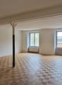 Empty room with wooden parquet flooring, white walls, two windows, and two pillars