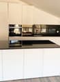 white kitchen, black countertops, integrated appliances, wooden flooring
