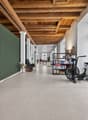 Open space with large wooden beams, white walls, white floor, green wall, living room items