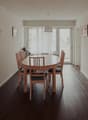 Dining room with wooden table, six chairs, wooden floor, and glass doors to a balcony