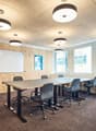 Modern empty meeting room with desks, chairs, whiteboard, and wooden paneling