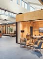 Open space office with wooden partition, glass wall, a couch, a coffee table, a plant, a table, and chairs.