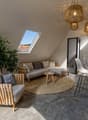 attic room with skylight, sofa, chairs, rug, table, potted plants, wooden furniture
