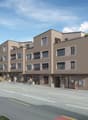 Multi-story residential building, modern design, multiple windows, rooftop terrace, street front, greenery