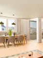 Dining room with wooden table, chairs, large windows, balcony, plant, rug, coffee table, couch