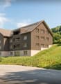 3 story house, brown exterior, multiple windows, balconies, located on a hill
