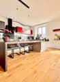 modern kitchen, large island, oak floor, stainless steel appliances, red cabinets, double oven, microwave, dishwasher, island stools