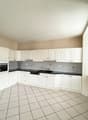White cabinets, white countertops, black countertops, white tiled floor, built-in oven and dishwasher