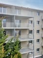 Multi-storey building, balconies, white exterior, modern design, trees in front