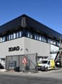 Office building, 3D/AG sign, multiple cars parked, two gates, construction scaffolding