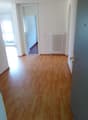 wooden floor, white walls, white radiator, glass window, doorway, hallway