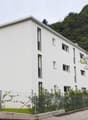 white building, several windows, fenced area, mountain in the background