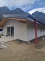 Newly constructed house, white exterior, gray roof, glass door, red chimney, construction materials around