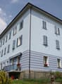 3 story white building, multiple windows, balcony, mountain view