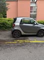 small silver car parked in parking lot in front of building