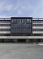 modern office building, glass facade, multiple floors, large windows, parking area