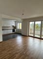 empty room, wooden floor, white walls, kitchen with appliances, sliding glass doors to balcony, radiator