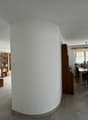 Empty room with a curved wall, a cabinet, a table, and a window.