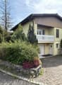2 story house, yellow exterior, white garage, balcony, driveway, garden