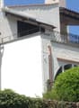 White stuccoed house, covered balcony with metal railings, chimney, metal guttering, glass window