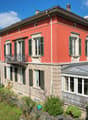 3 story house, red exterior, white windows, balcony, glass conservatory, garden