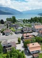 Aerial view of a neighborhood with houses, a lake, and mountains in the background