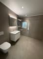 modern bathroom with white sink, mirror, toilet, and glass shower enclosure
