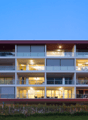 Modern multi-story residential building, multiple balconies, mountain view