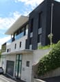 Modern house, black and white exterior, large windows, garage, concrete wall, greenery