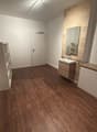 empty room, wooden floors, white walls, ceiling lamp, mirror, sink, cabinets