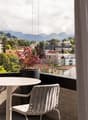 outdoor balcony with table and chairs, glass railing, potted plant, city view, mountain view