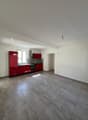 Empty kitchen with red cabinets, gray tiled floor, white walls, window, stove, sink, and a lamp
