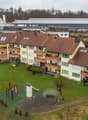 Apartment complex with yellow exterior walls, brown roofs, balconies, and playground in the front.