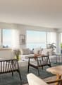 modern living room, large windows, white furniture, wooden table, rug, plants, view of the sea