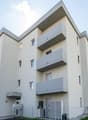 Modern white building, multiple balconies, multiple floors, fenced area in front