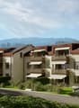 Three story residential building, solar panels, white and brown walls, balconies, fenced garden