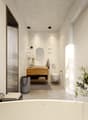 Bathroom with large bathtub, wooden vanity, toilet, mirror, modern lighting, and plant
