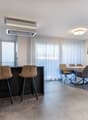 Countertop, bar stools, round table with chairs, large glass doors, green plant