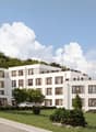 Modern white building, multiple floors, multiple balconies, green lawn, trees, cars parked in front