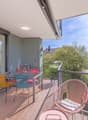 Balcony with wooden floor, metal railing, table and chairs, glass doors, couch, view of trees and mountains
