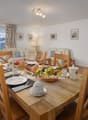 dining table, wooden chairs, large windows, view of mountains, breakfast set, couch, lamp