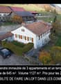White house with brown roof, car parked, garden, green field, mountains in the distance