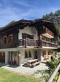 2-story wooden house, wooden balconies, white walls, wooden double doors, wooden picnic table, outdoor seating, wooden fence, grassy yard, mountainous landscape