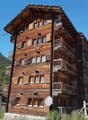 wooden building, multiple balconies, multiple windows, mountains in the background