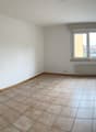 empty room with white walls, tiled floor, large window, heating radiator